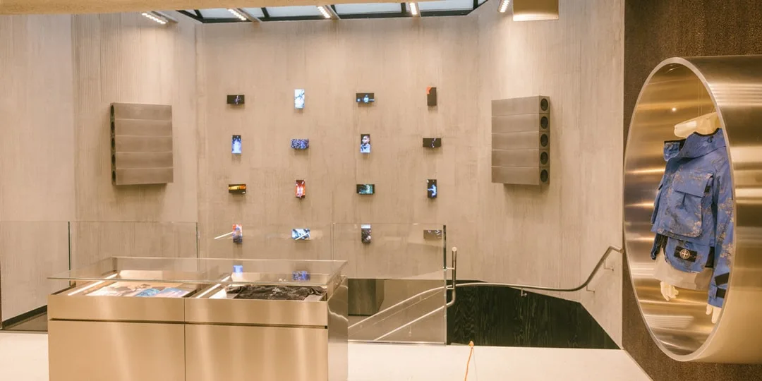 Intérieur d'un magasin moderne avec des vêtements et des écrans exposés au mur.
