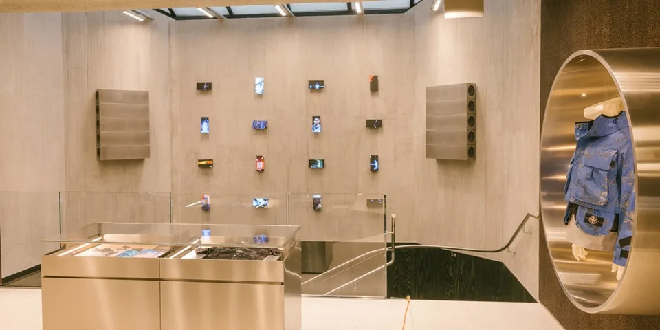 Intérieur d'un magasin moderne avec des vêtements et des écrans exposés au mur.