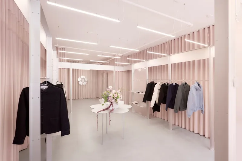 Boutique moderne avec vêtements affichés et rideaux roses.