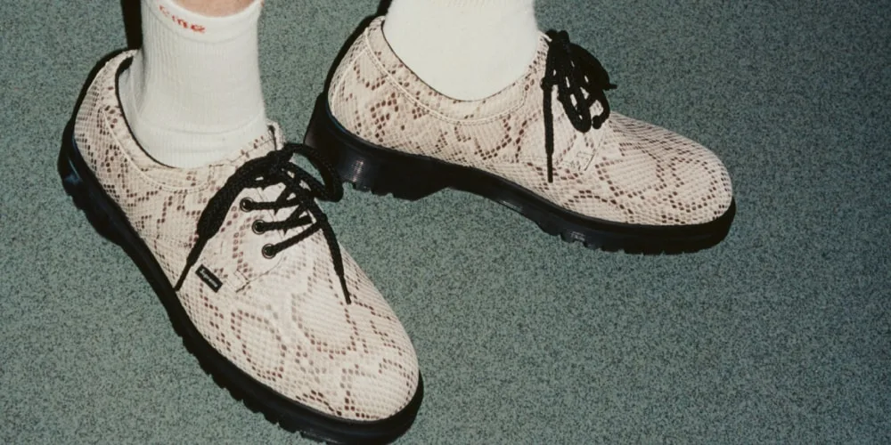 Chaussures à motif serpent avec lacets noirs sur sol vert.