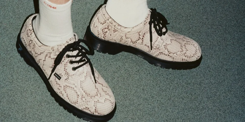 Chaussures à motif serpent avec lacets noirs sur sol vert.