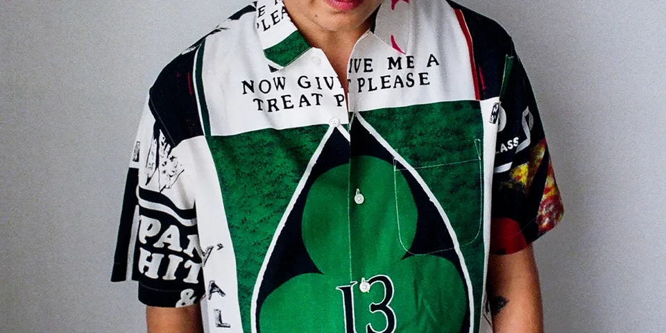 Homme portant une chemise colorée avec des motifs et du texte.