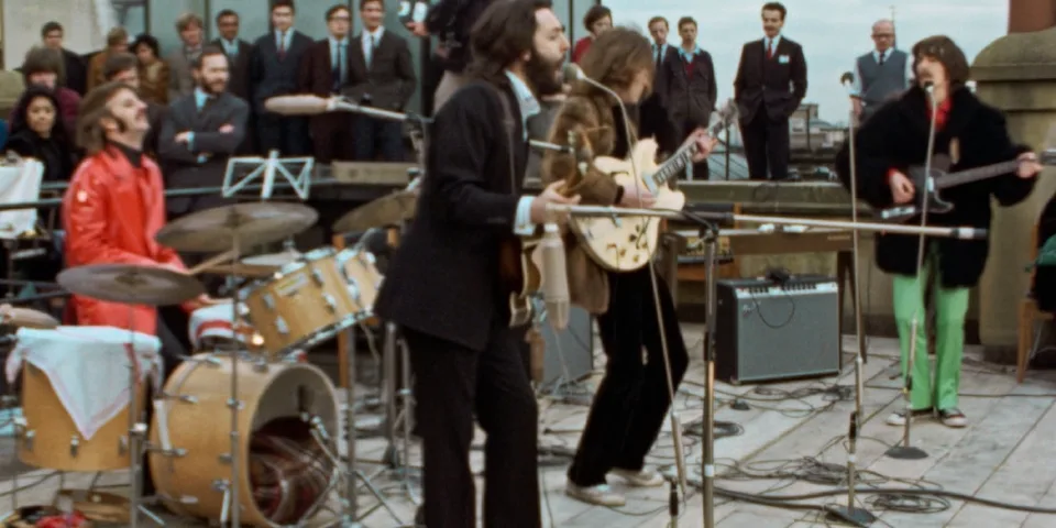 Groupe joue sur un toit devant un public, instruments en fond.