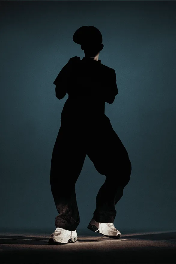Silhouette d'une personne posant dans l'obscurité avec des vêtements amples.