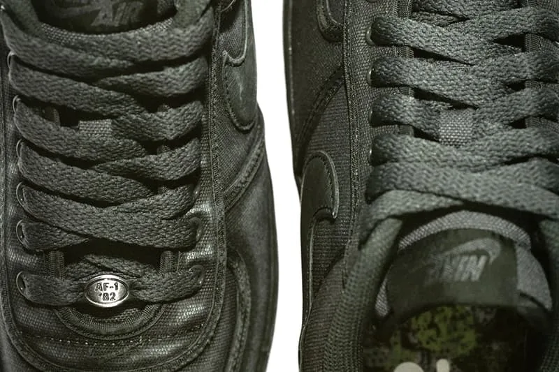 Gros plan sur des baskets noires avec logos et textures visibles.