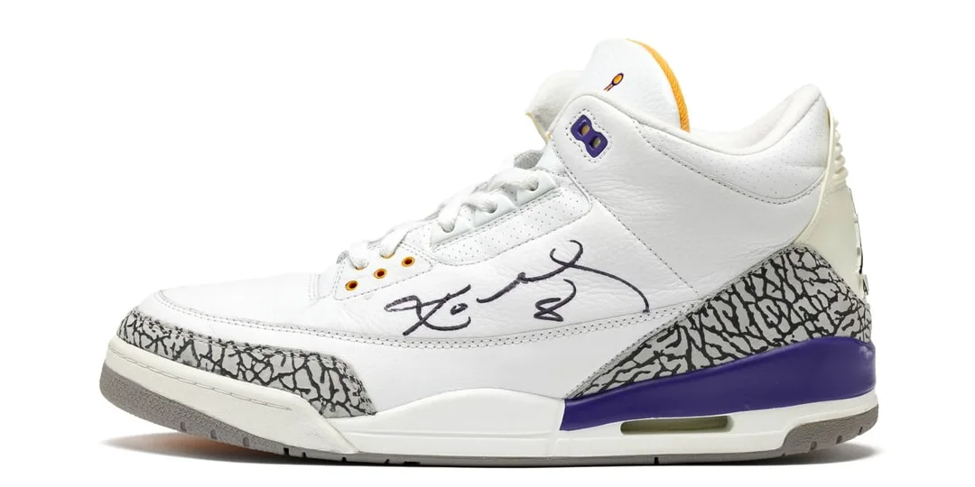 Chaussure blanche avec motifs gris et accent violet, signée au stylo.