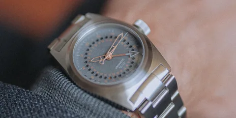 Montre-bracelet en acier avec cadran noir et aiguilles dorées.