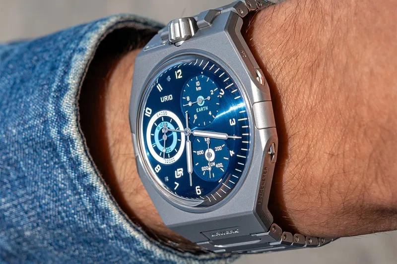 Montre bleue et argentée au poignet, cadran complexe.