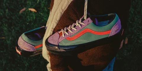 Personne tenant des chaussures colorées sur un fond d'herbe.