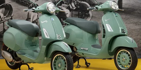 Deux scooters verts Vespa exposés sur un fond vintage.
