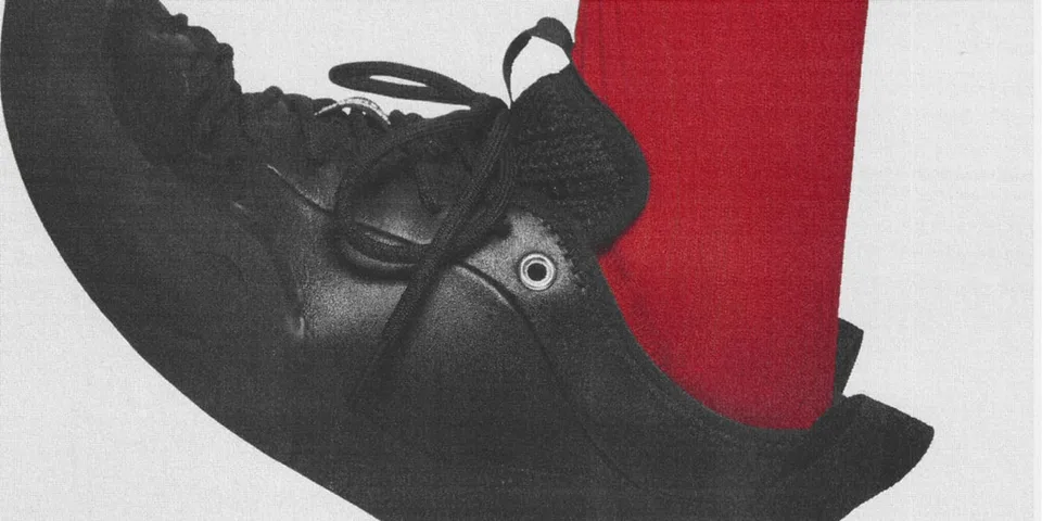 Chaussure noire avec chaussette rouge visible.
