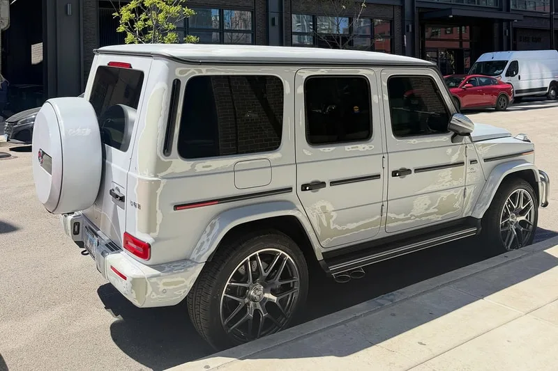 Voiture de luxe blanche garée dans la rue avec des roues stylisées.