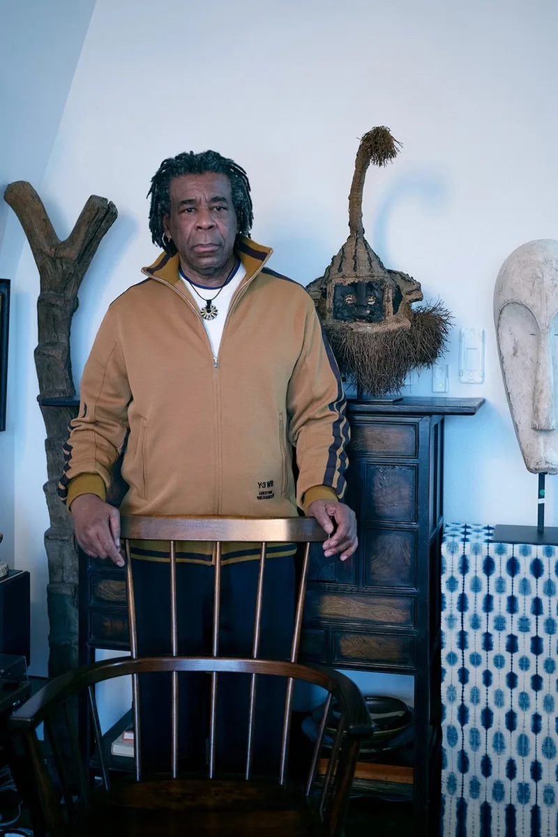 Homme debout avec statues et objets d'art en arrière-plan.