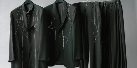 Costumes noirs avec motifs de couture blanche sur cintres.