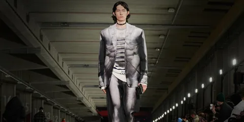 Un mannequin défile avec un costume moderne dans un espace industriel.